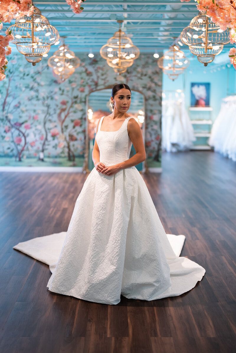 A woman in a white wedding dress is standing in a room.