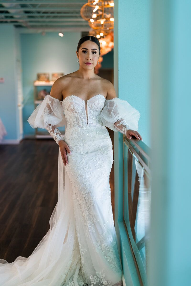 A woman in a wedding dress is leaning against a railing.