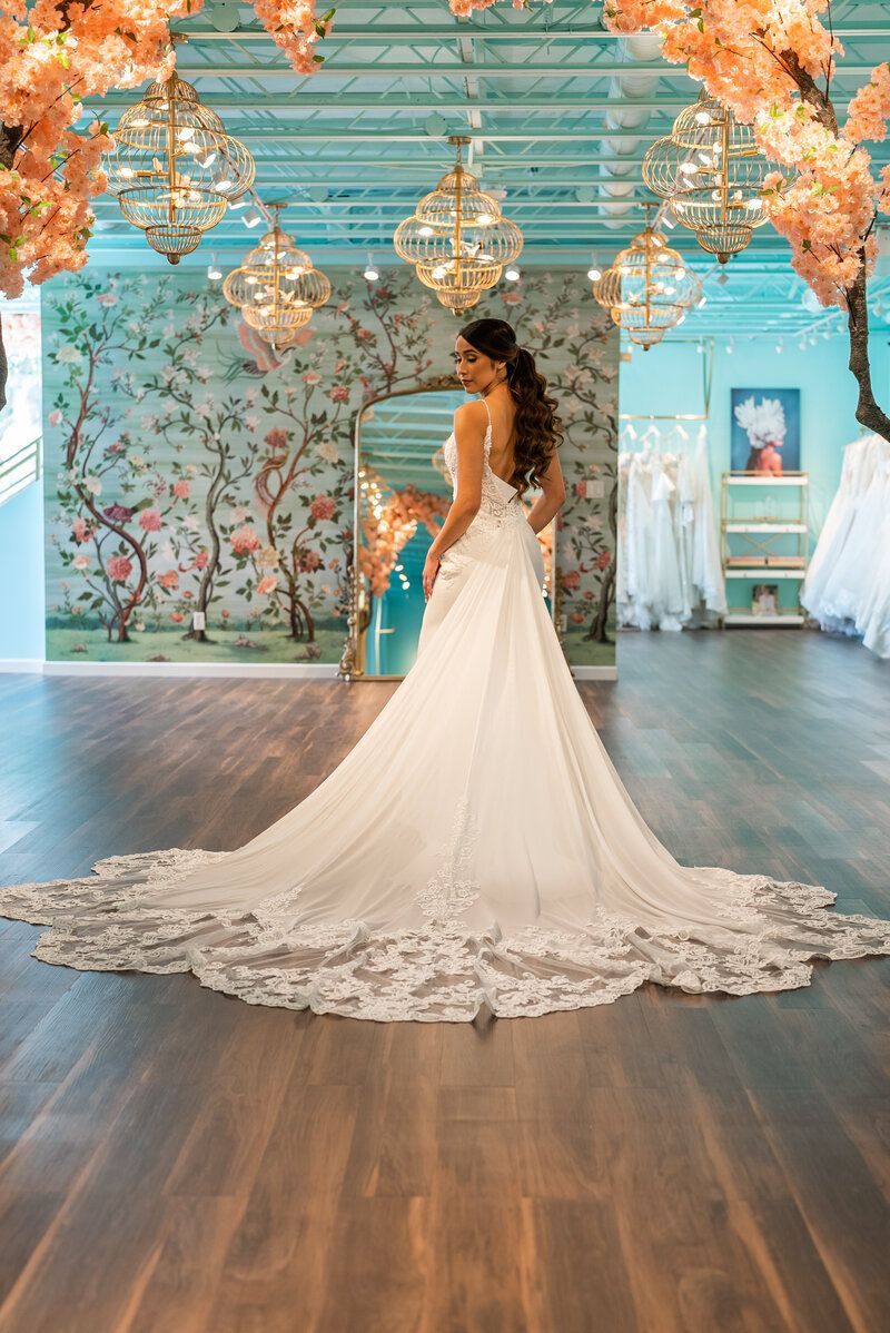 A woman in a wedding dress is standing in front of a mirror in a room.