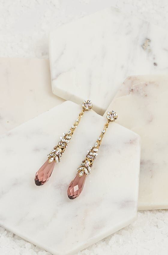 A pair of earrings are sitting on top of a white marble block.
