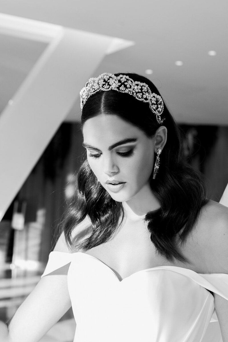 A black and white photo of a woman in a wedding dress wearing a tiara.