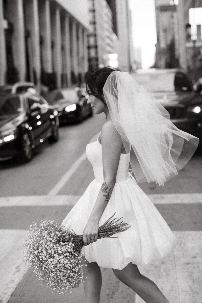 The bride is wearing a veil and holding a bouquet of baby 's breath.