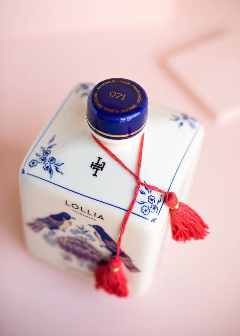A bottle of lollia sits on a pink surface