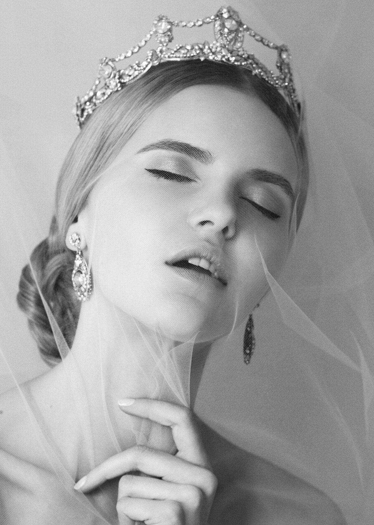 A black and white photo of a woman wearing a tiara and veil.
