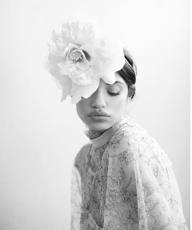 A woman is wearing a large white flower in her hair.