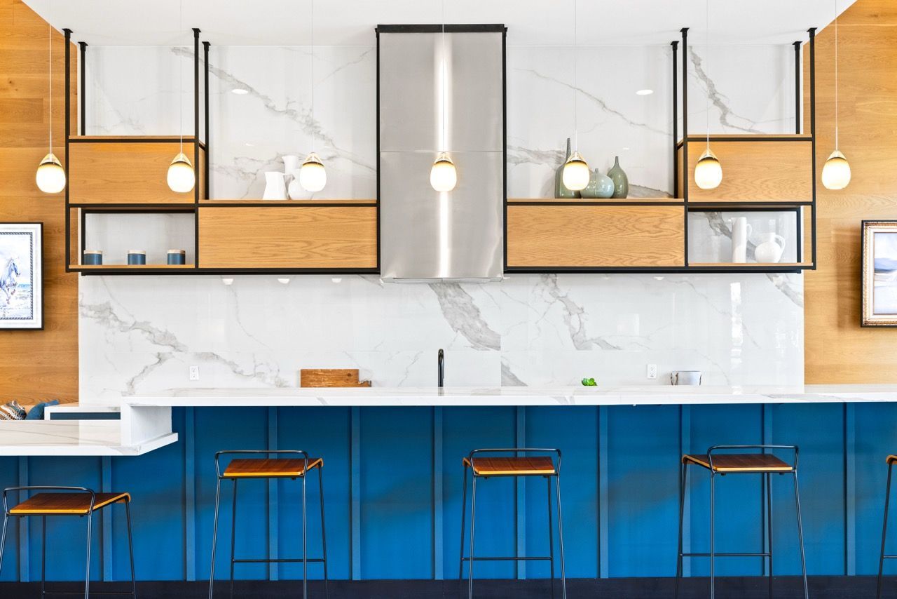 Modern kitchen with blue island, marble backsplash, and bar stools.