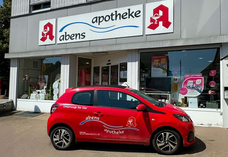 Vor einer Apotheke parkt ein rotes Auto.