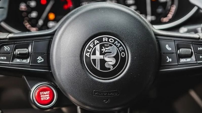 Alfa Romeo steering wheel with logo and controls, start/stop button.