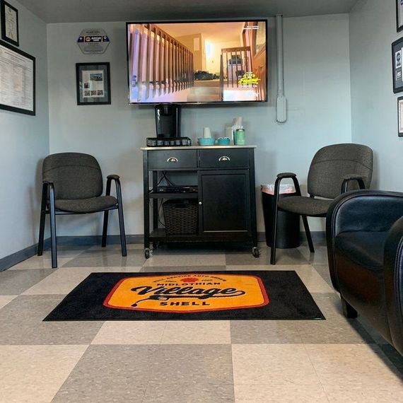 Waiting room with chairs, TV, and coffee station. A rug on the checkered floor has