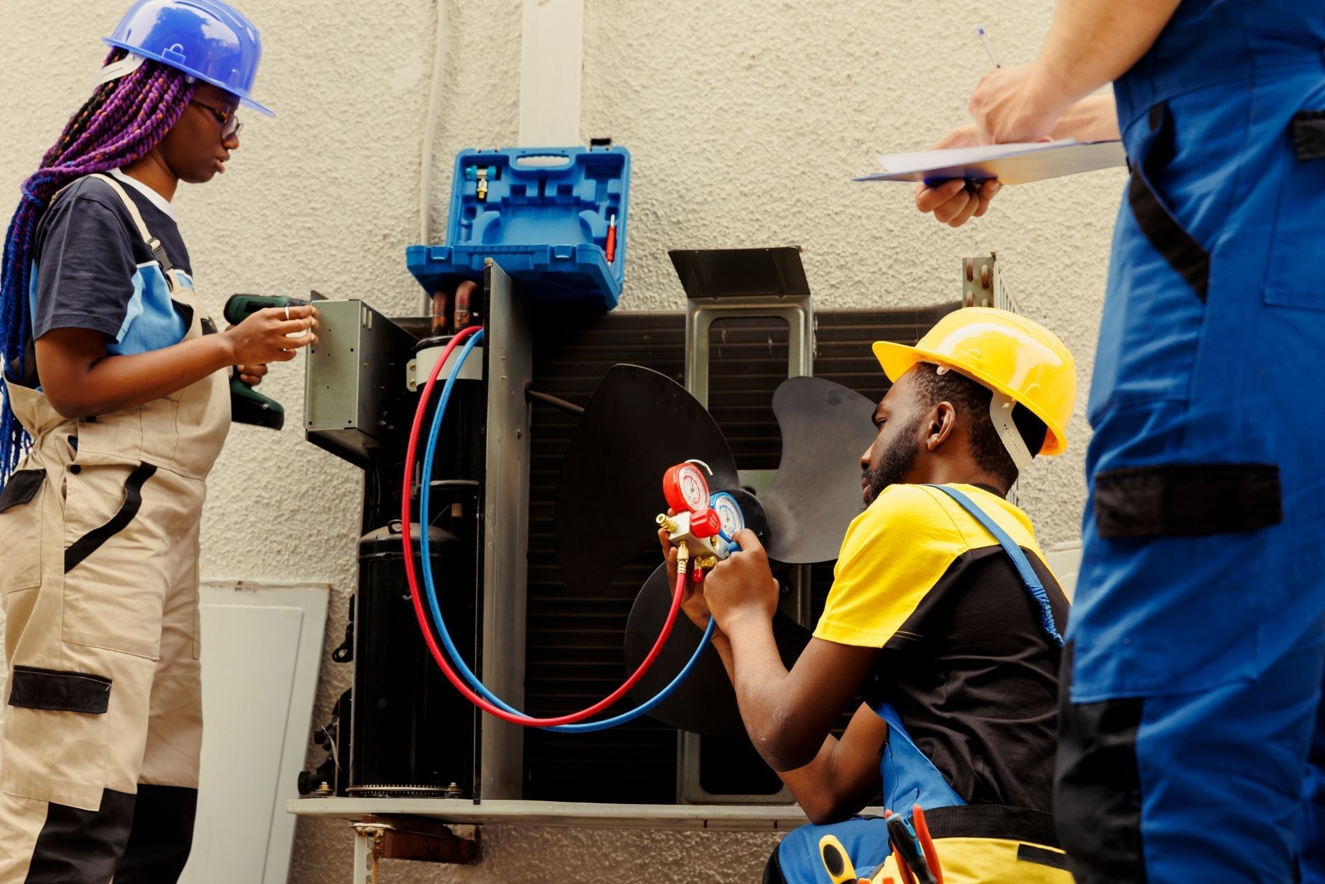 HVAC technician wearing mask and hard hat, working on AC units on a rooftop.