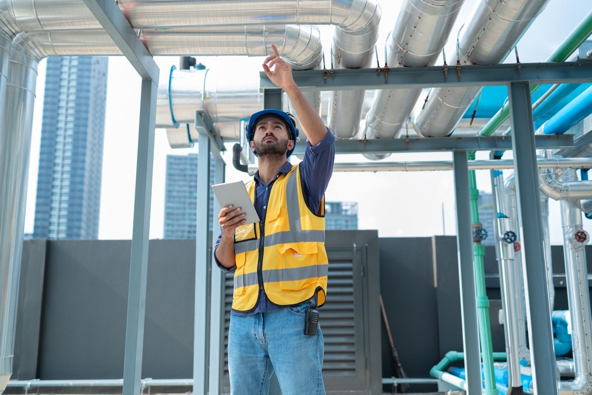 HVAC technician wearing mask and hard hat, working on AC units on a rooftop. HVAC technician wearing mask and hard hat, working on AC units on a rooftop.