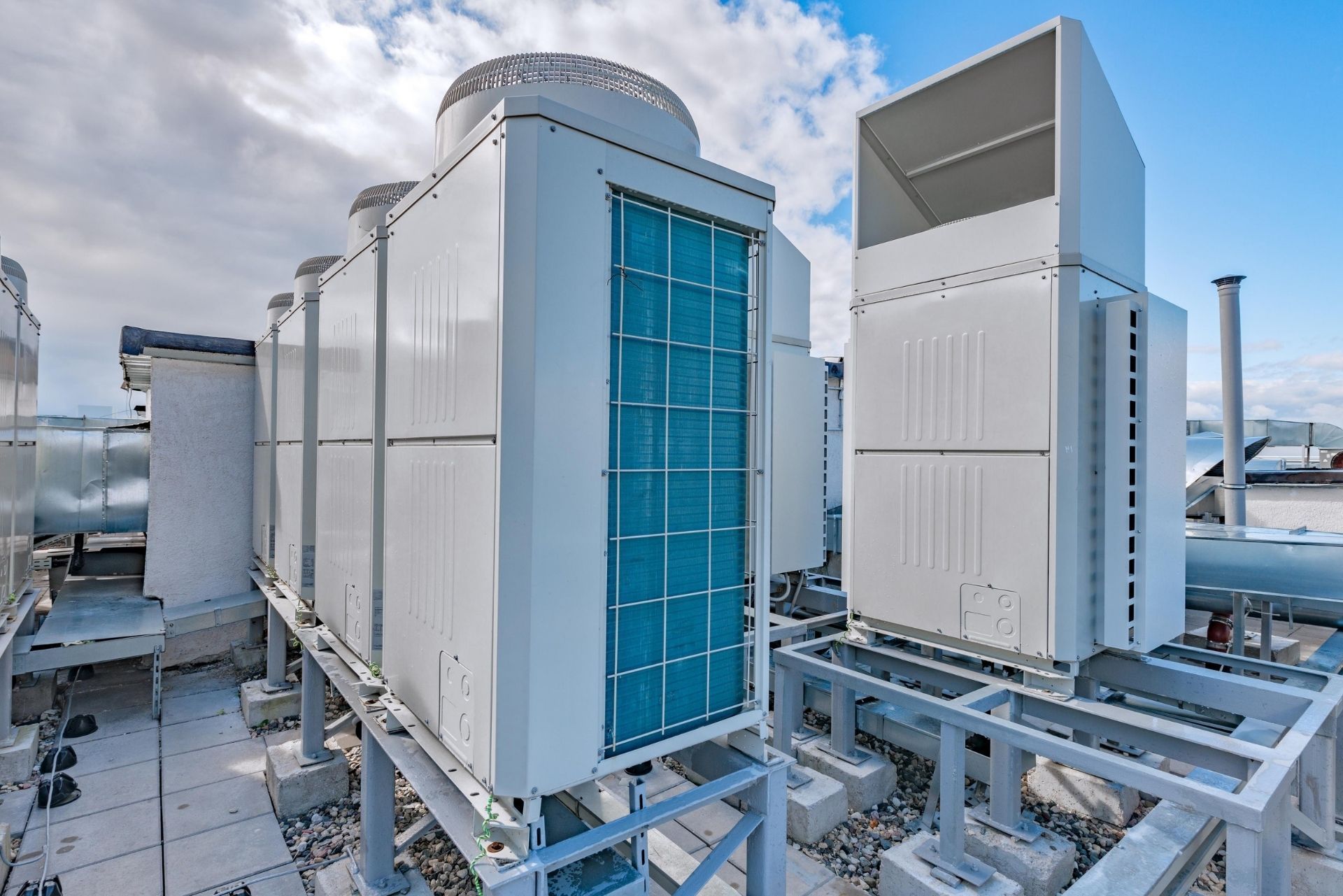 HVAC technician wearing mask and hard hat, working on AC units on a rooftop. HVAC technician wearing mask and hard hat, working on AC units on a rooftop.