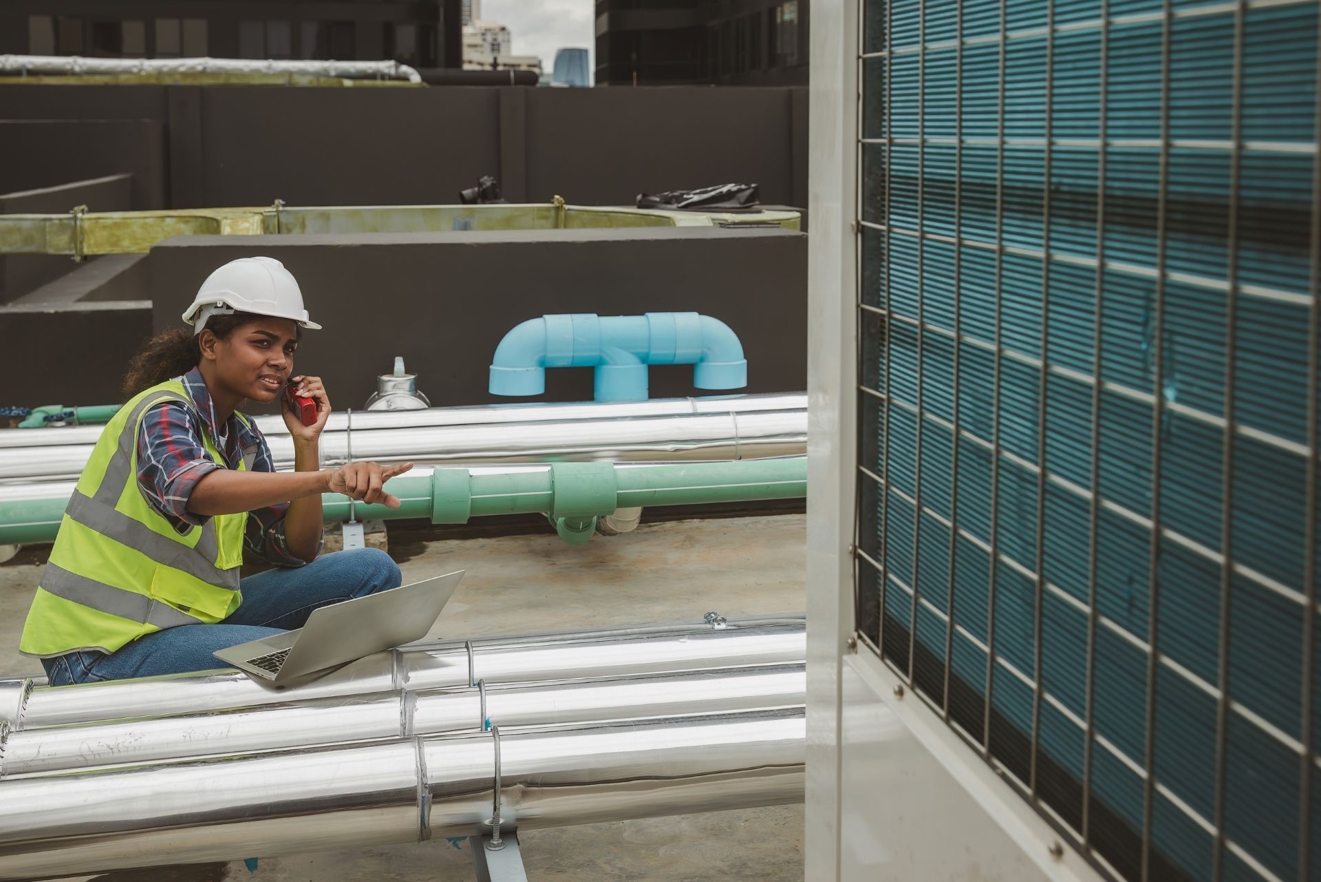 HVAC technician wearing mask and hard hat, working on AC units on a rooftop. HVAC technician wearing mask and hard hat, working on AC units on a rooftop.