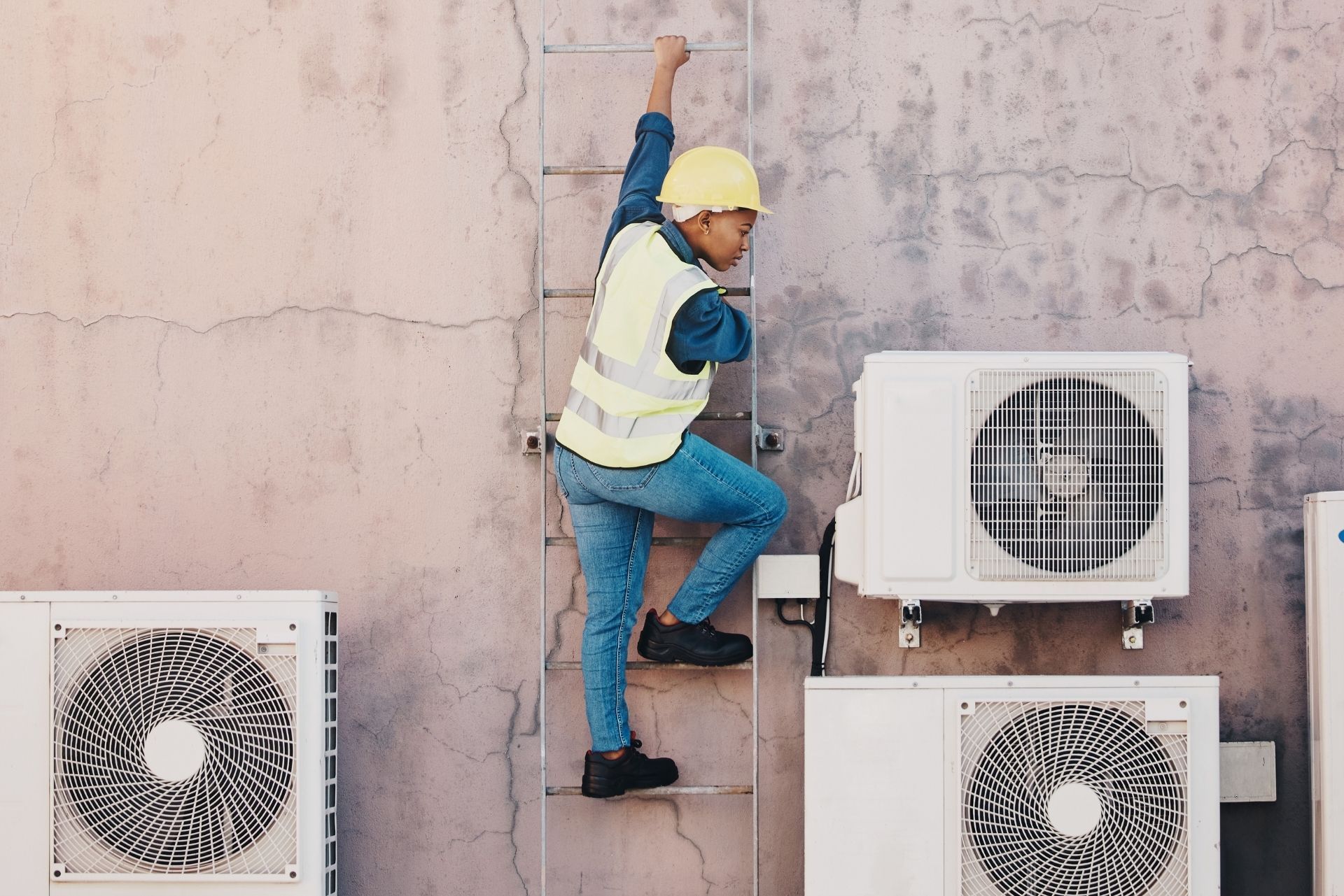 HVAC technician wearing mask and hard hat, working on AC units on a rooftop. HVAC technician wearing mask and hard hat, working on AC units on a rooftop.