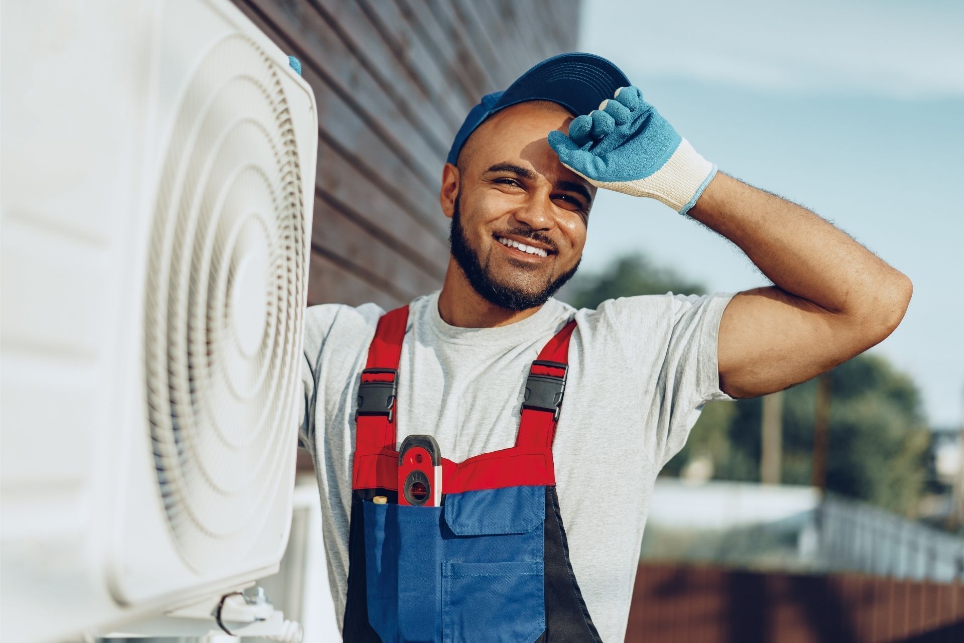 HVAC technician wearing mask and hard hat, working on AC units on a rooftop. HVAC technician wearing mask and hard hat, working on AC units on a rooftop.