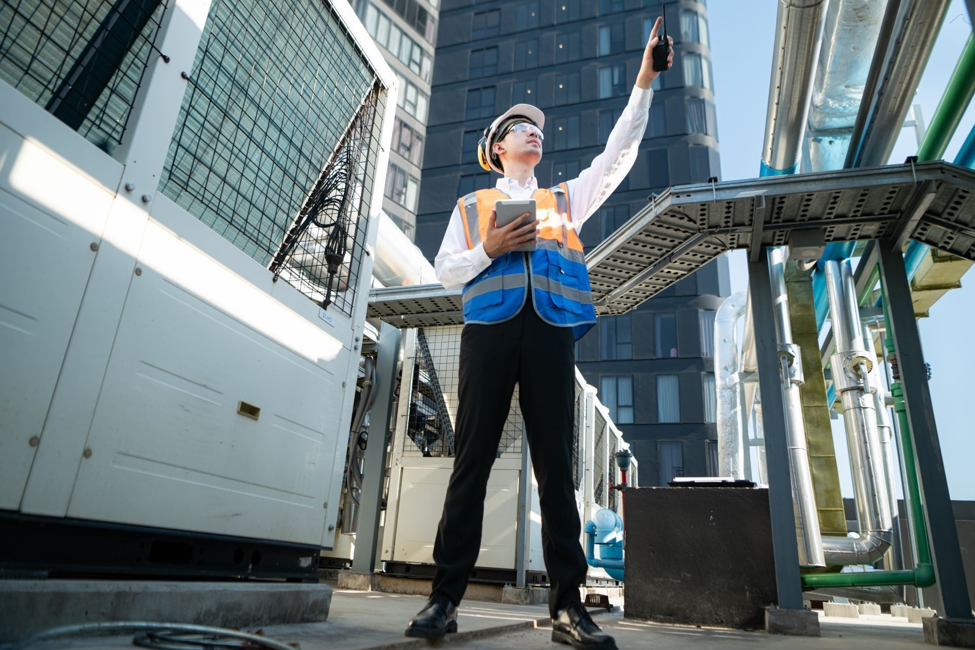 HVAC technician wearing mask and hard hat, working on AC units on a rooftop. HVAC technician wearing mask and hard hat, working on AC units on a rooftop.