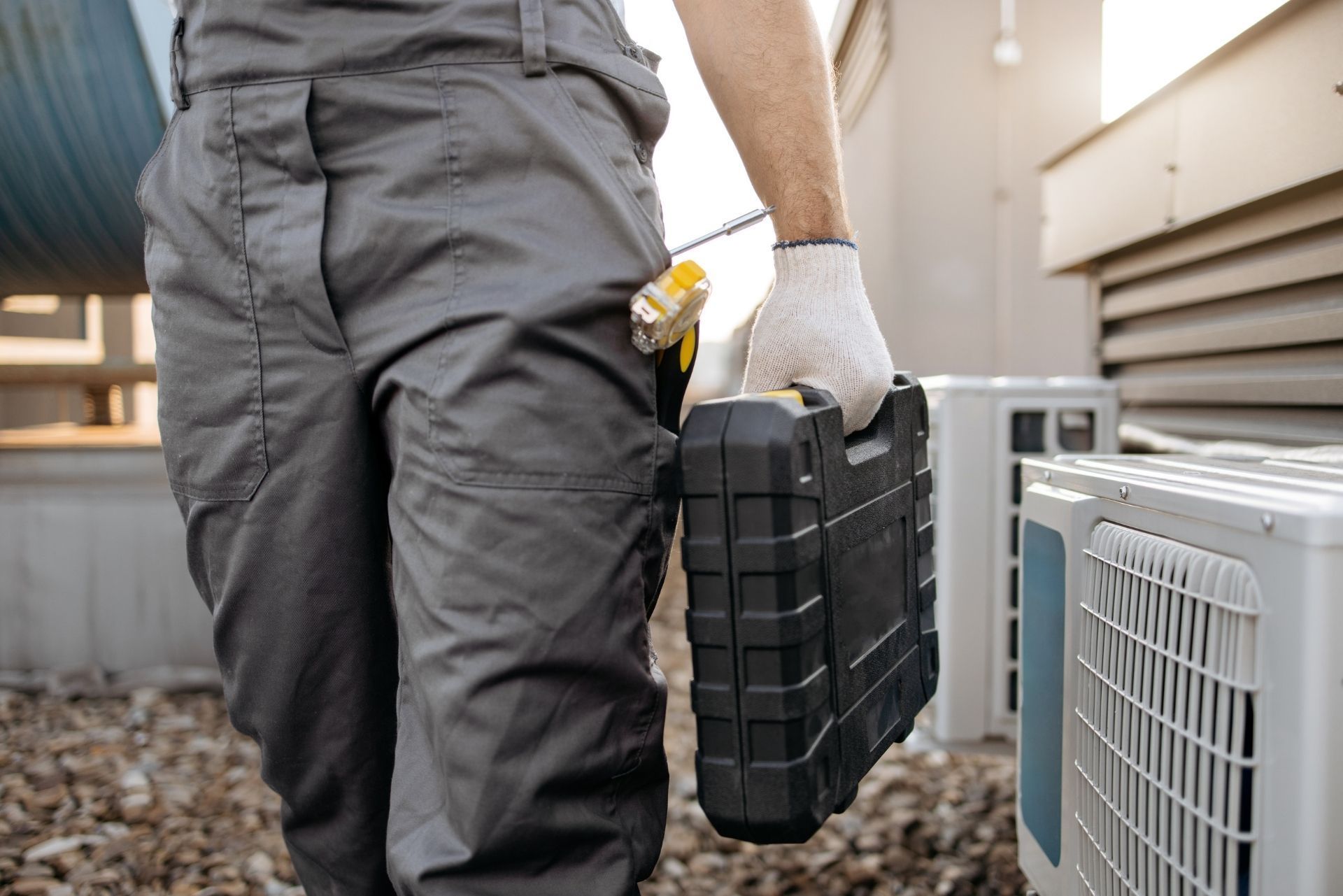 HVAC technician wearing mask and hard hat, working on AC units on a rooftop. HVAC technician wearing mask and hard hat, working on AC units on a rooftop.