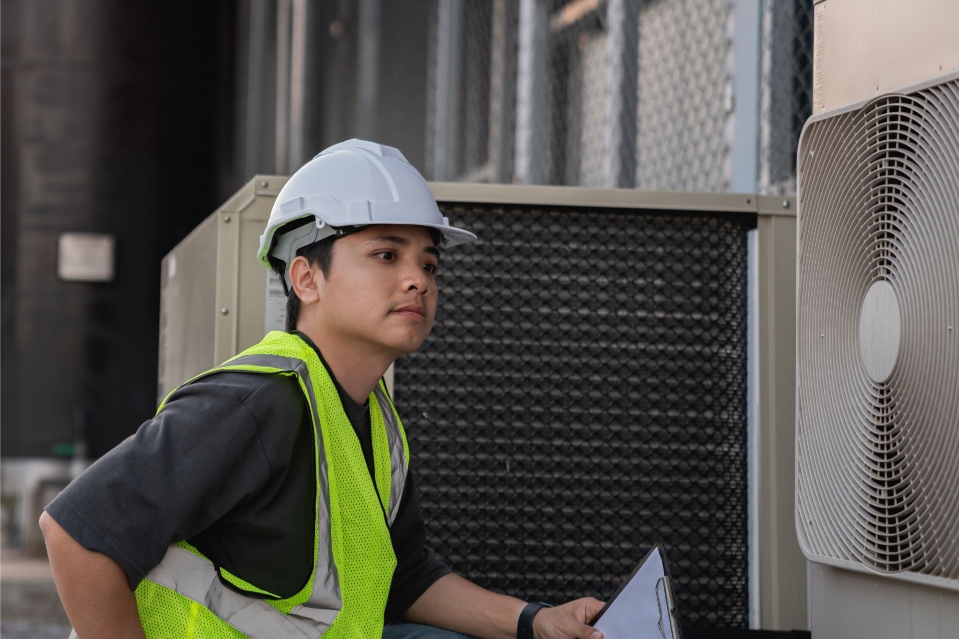HVAC technician wearing mask and hard hat, working on AC units on a rooftop. HVAC technician wearing mask and hard hat, working on AC units on a rooftop.