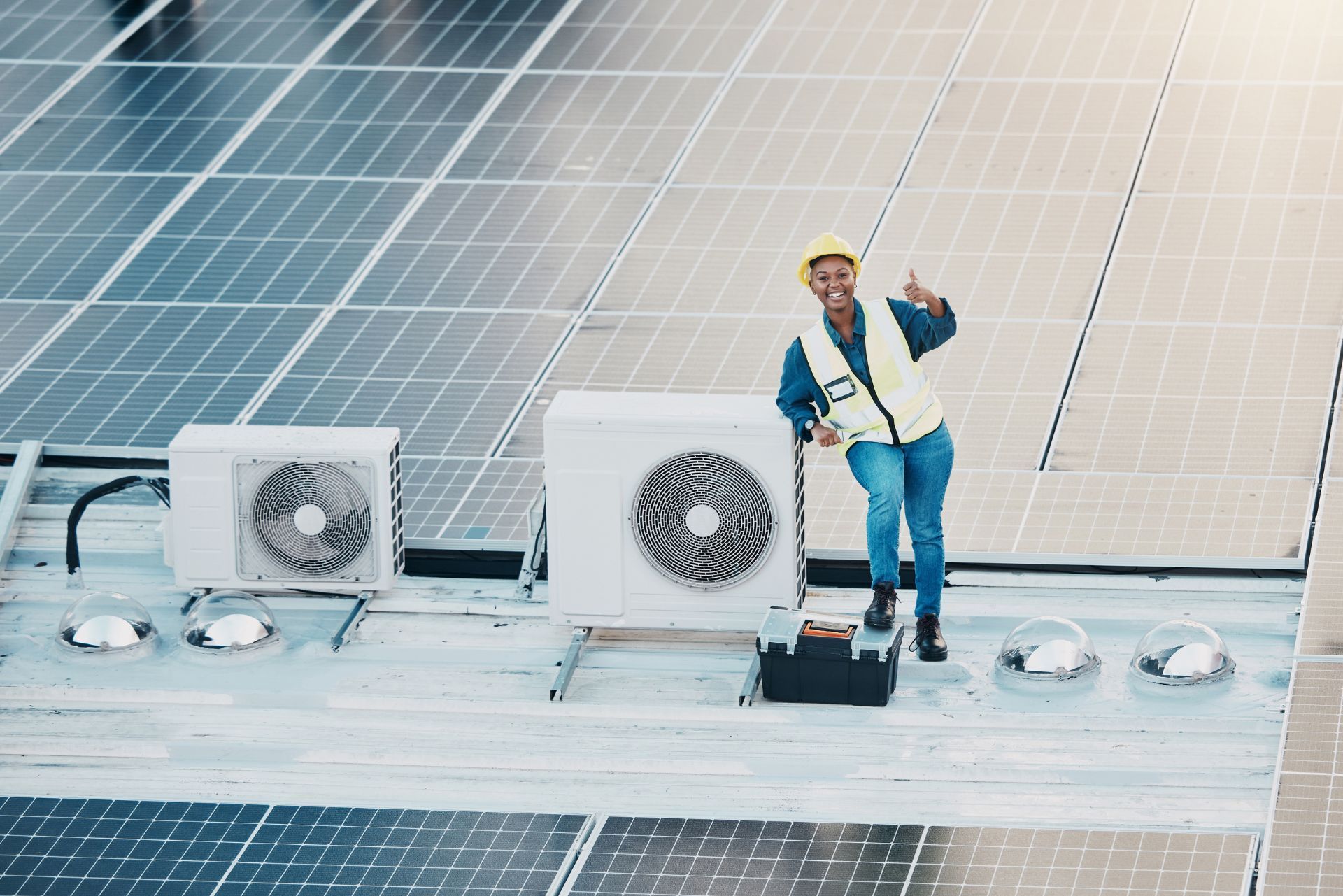HVAC technician wearing mask and hard hat, working on AC units on a rooftop. HVAC technician wearing mask and hard hat, working on AC units on a rooftop.
