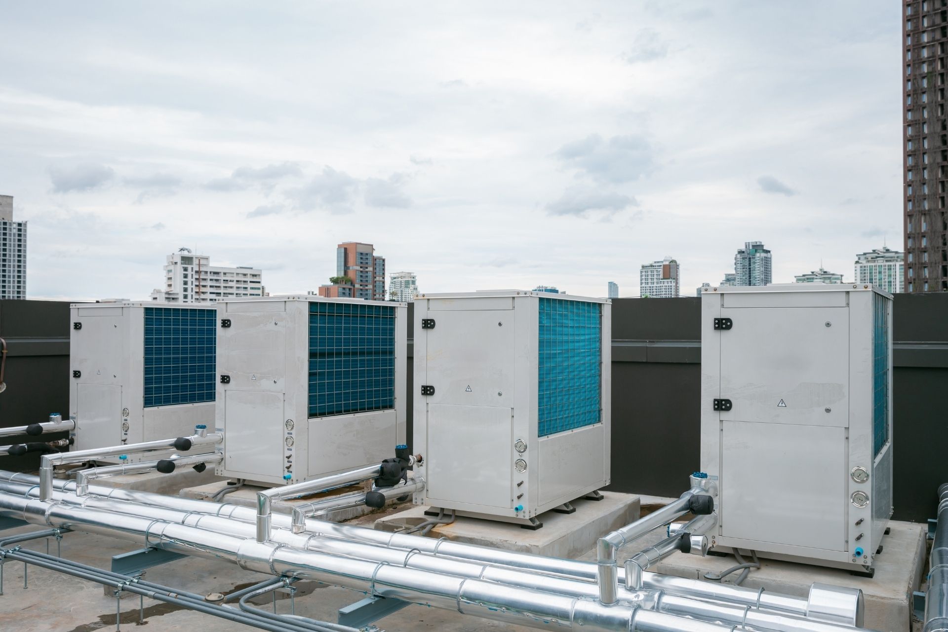 HVAC technician wearing mask and hard hat, working on AC units on a rooftop. HVAC technician wearing mask and hard hat, working on AC units on a rooftop.