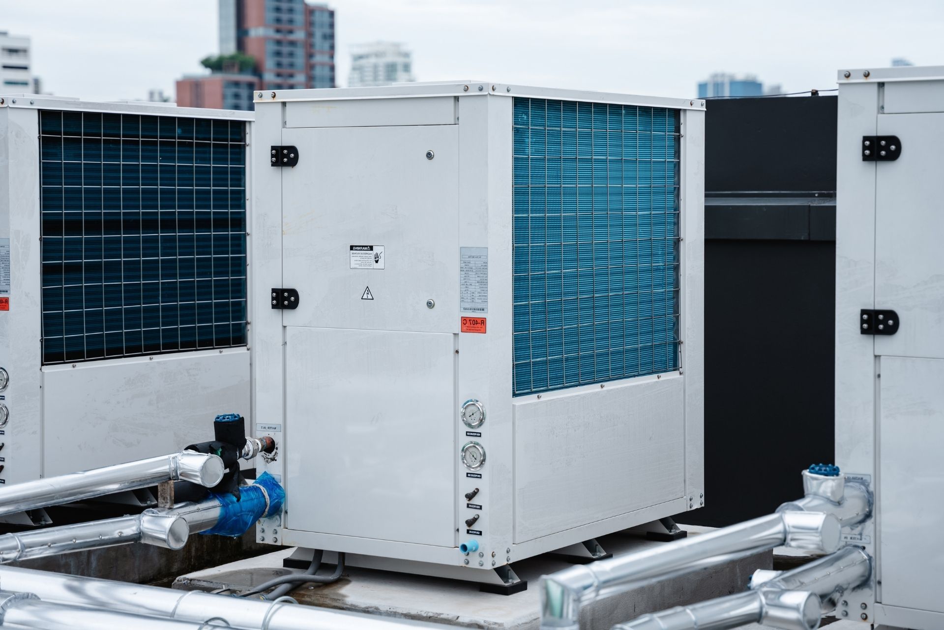 HVAC technician wearing mask and hard hat, working on AC units on a rooftop. HVAC technician wearing mask and hard hat, working on AC units on a rooftop.