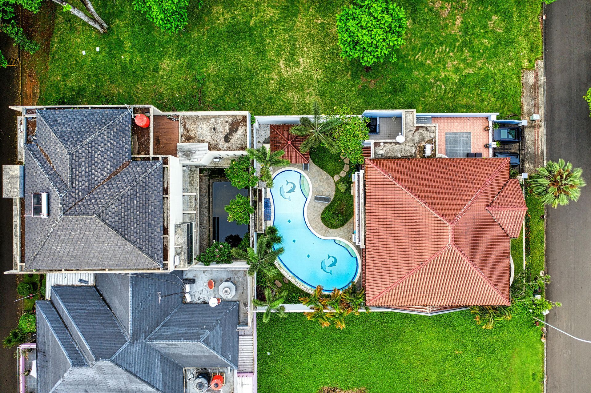 Aerial view of two houses beside a backyard with a blue swimming pool and green lawn.