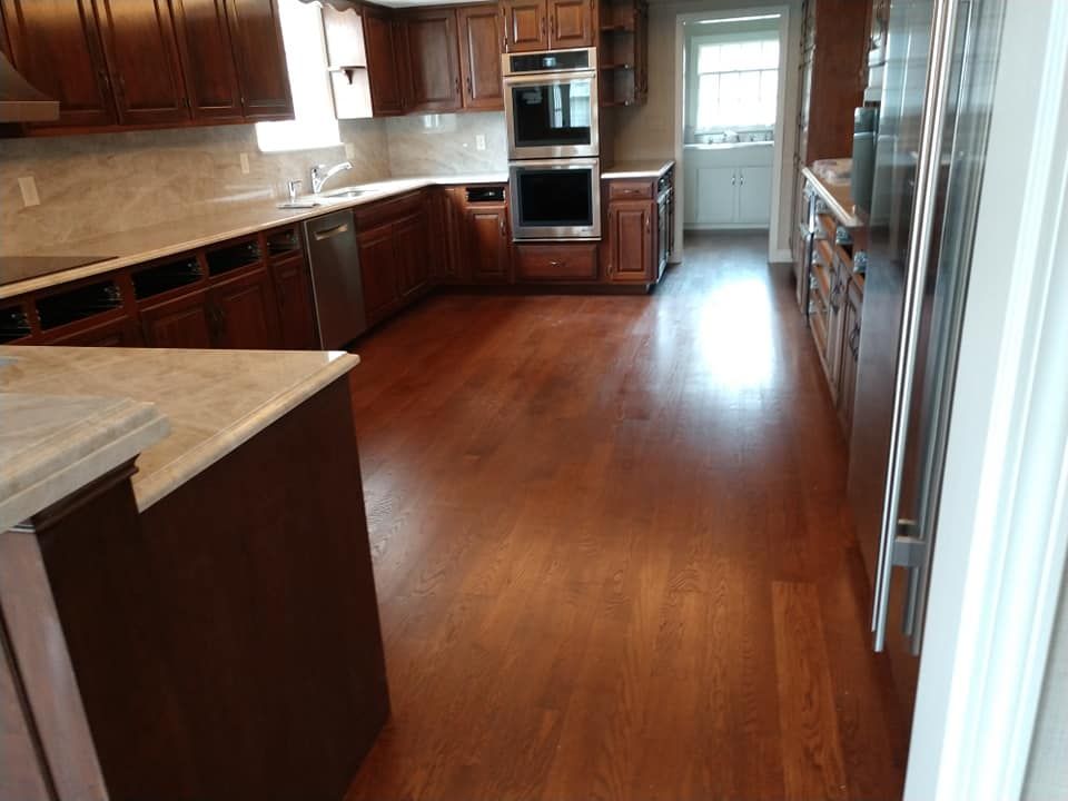 Kitchen with dark wood cabinets, light countertops, stainless steel appliances, and hardwood floors.