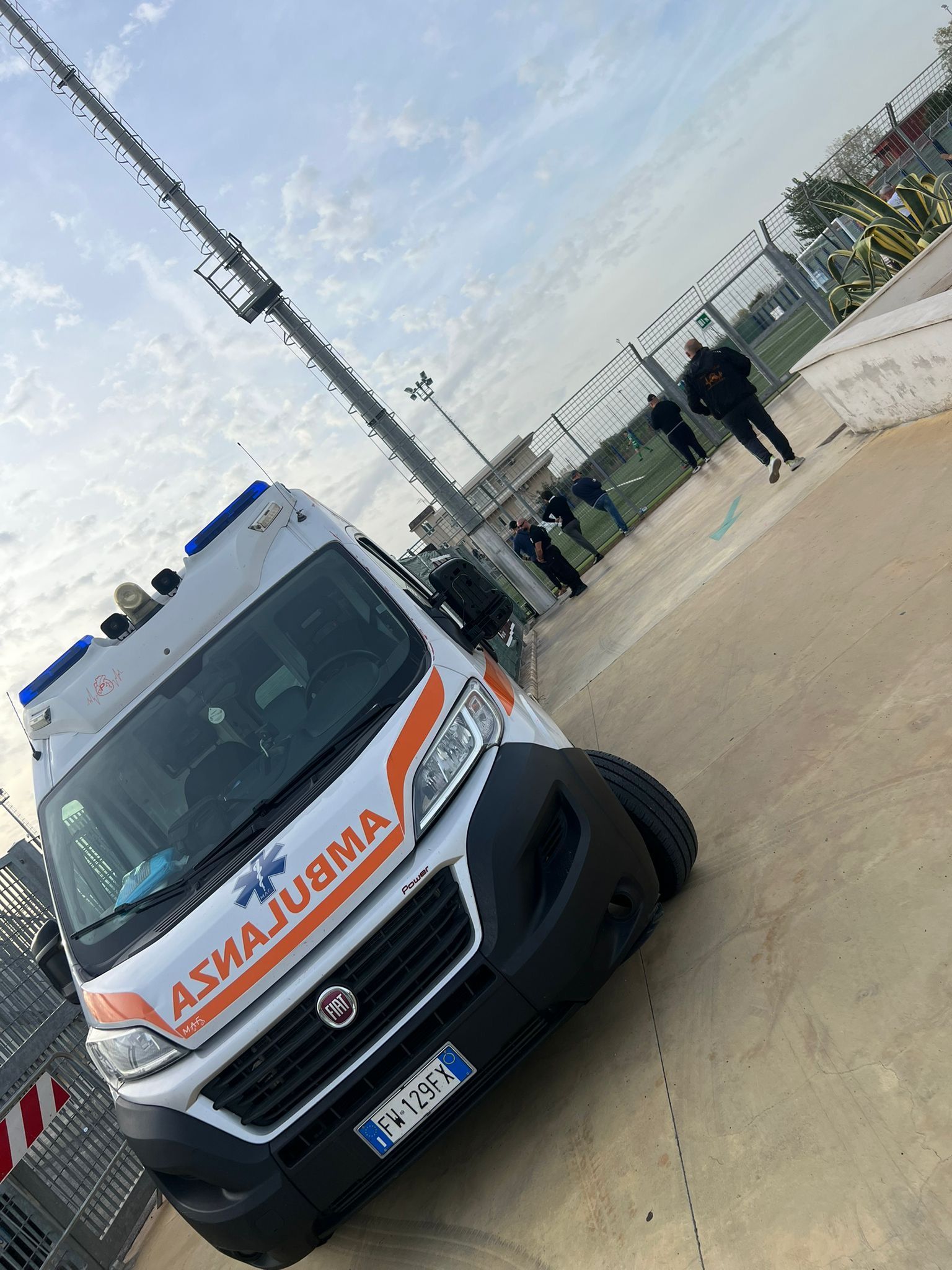 Un'ambulanza è parcheggiata di traverso sul ciglio della strada, con un marciapiede pedonale e pali della luce nelle vicinanze.