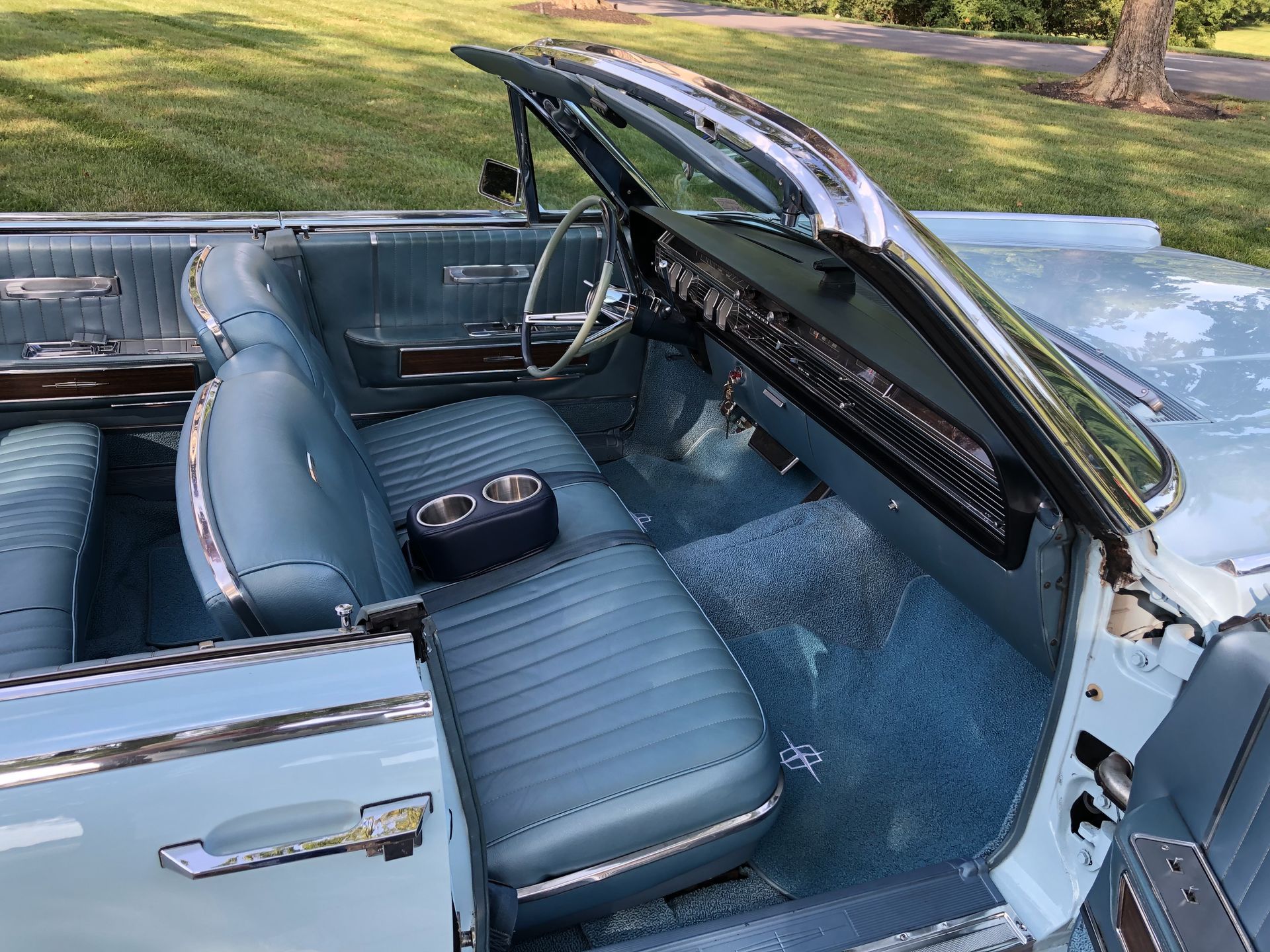 Blue interior of a vintage convertible car with light blue seats and a black center console.