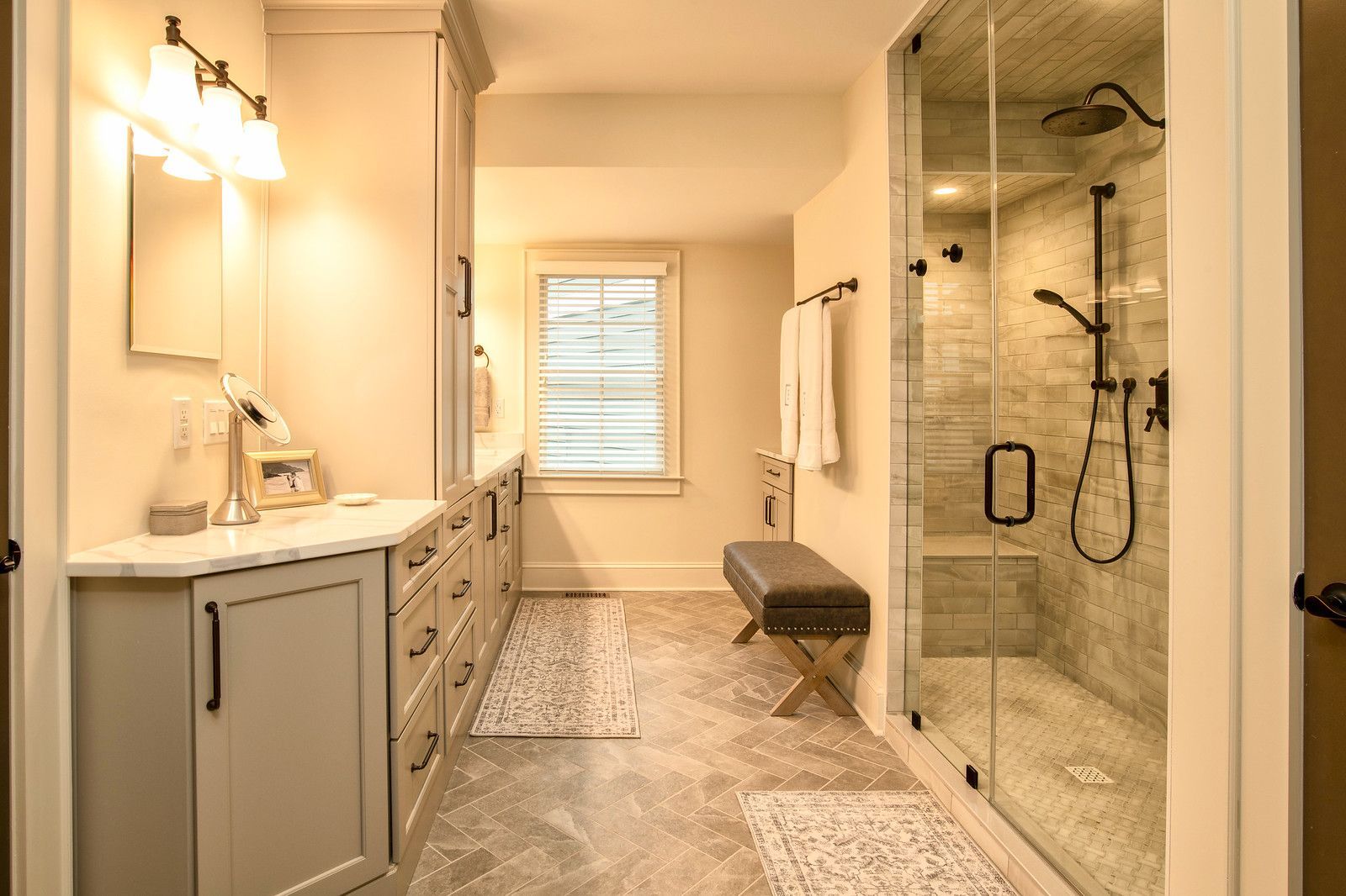 Bright modern bathroom with vanity, walk-in glass shower, tub, and patterned floor rug