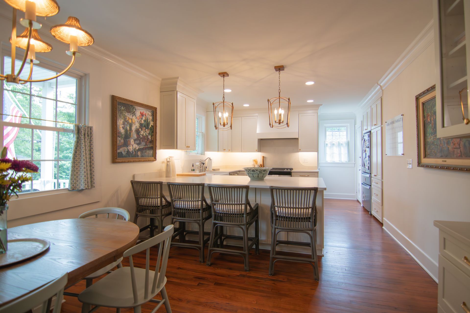 Bright dining room with wooden table, chairs, white island, hanging lights, and hardwood floors