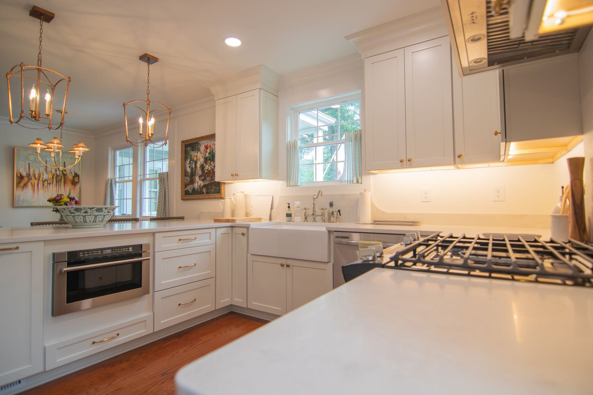 Bright white kitchen with island, gas range, pendant lights, and large windows