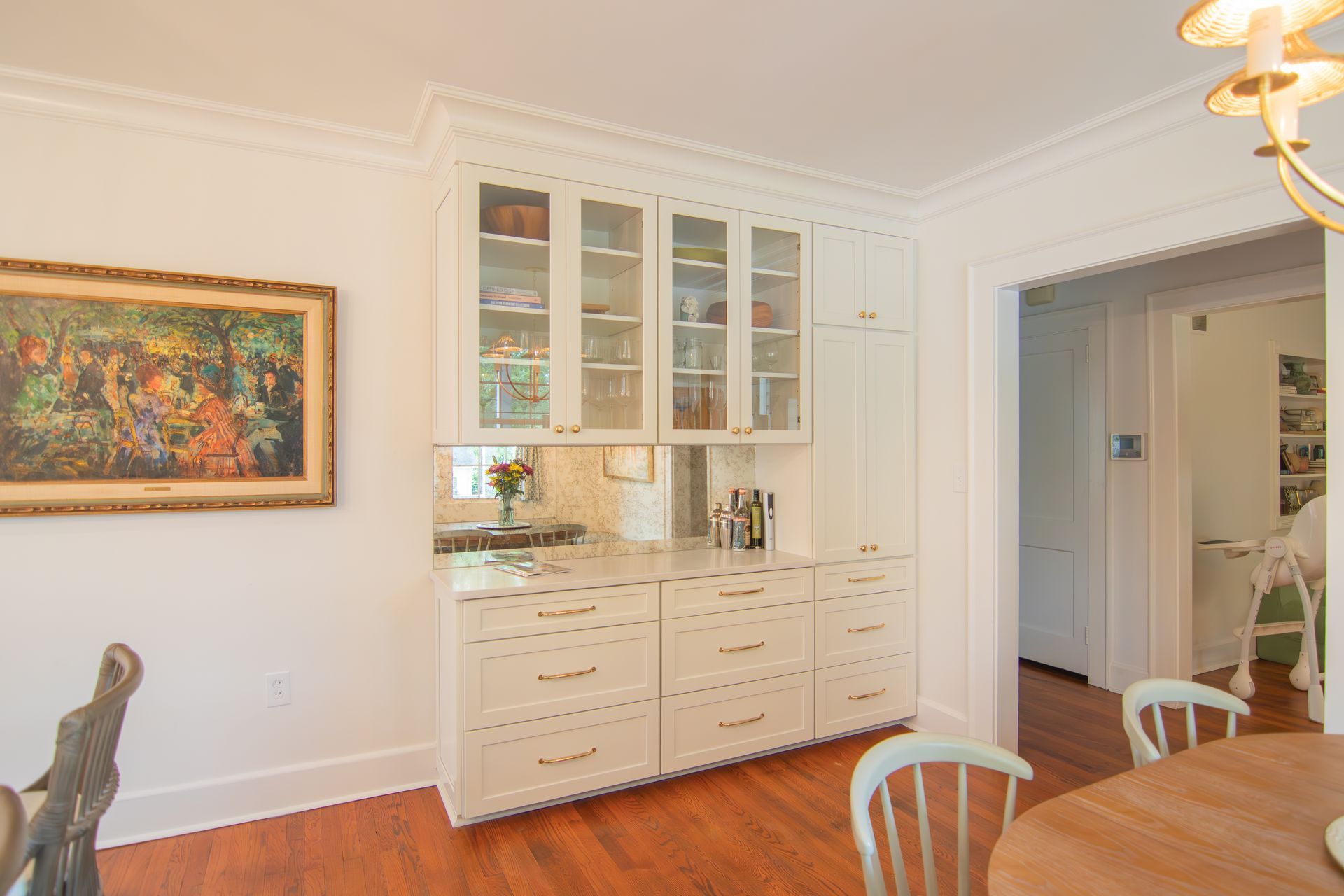 Bright dining room with white built-in cabinets, a wooden table, wall art, and a doorway to another room