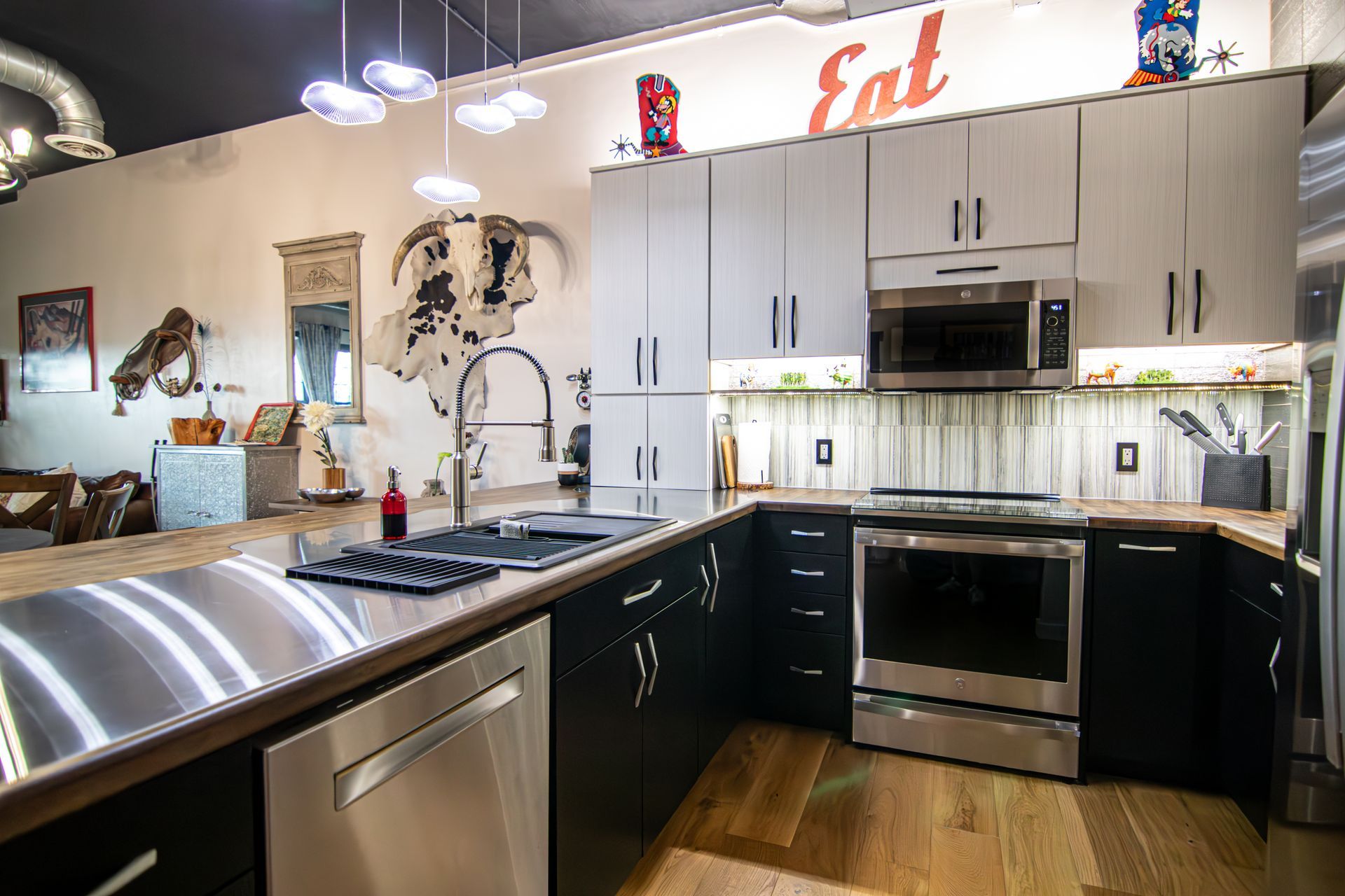Modern kitchen with stainless steel appliances, black and white cabinets, and pendant lights