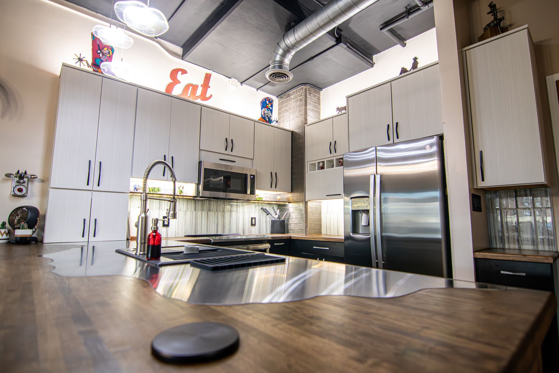 Modern kitchen with stainless steel appliances, white cabinets, and a large wooden table in the foreground