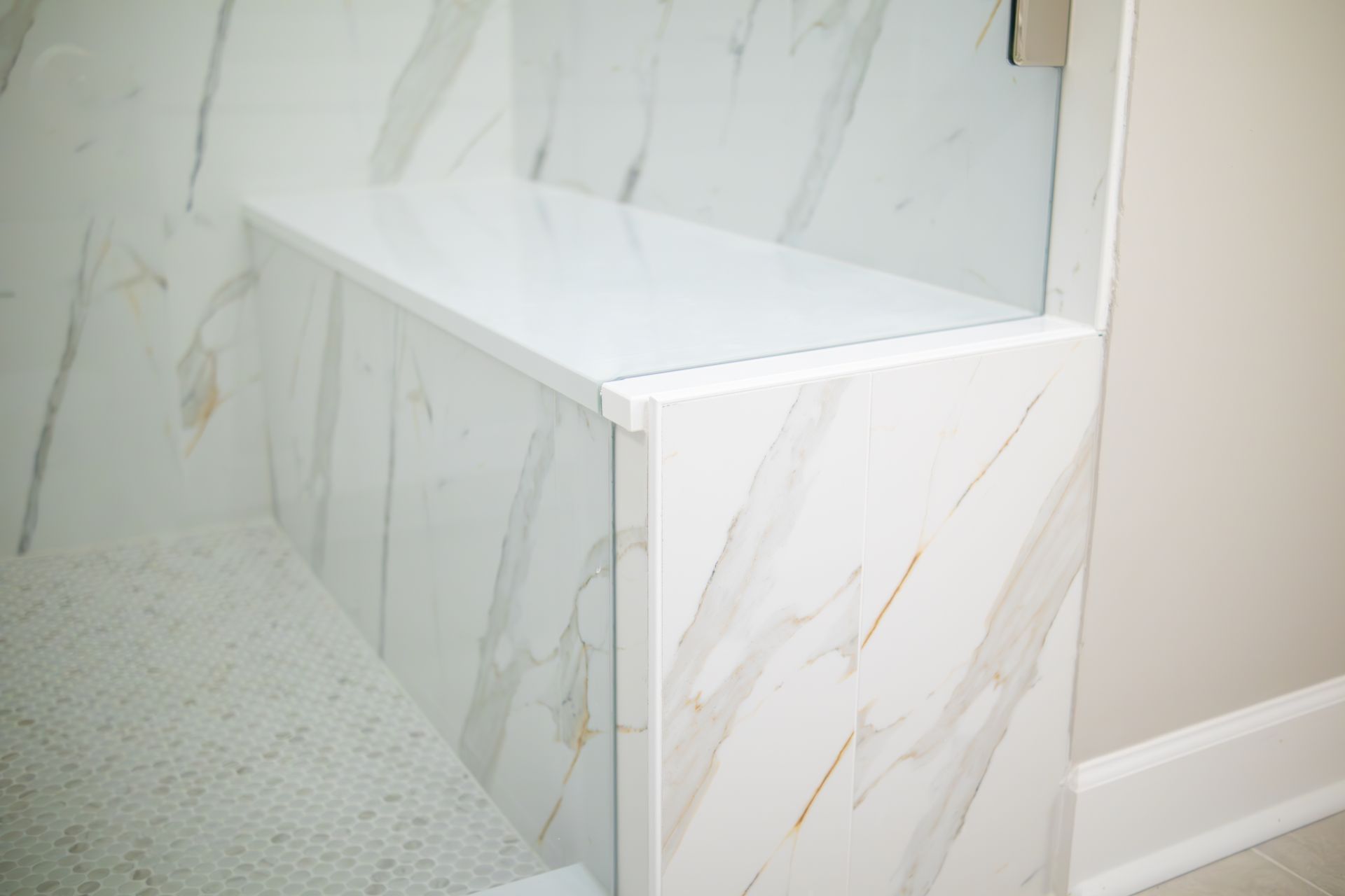 Built-in white marble-look shower bench in a tiled bathroom
