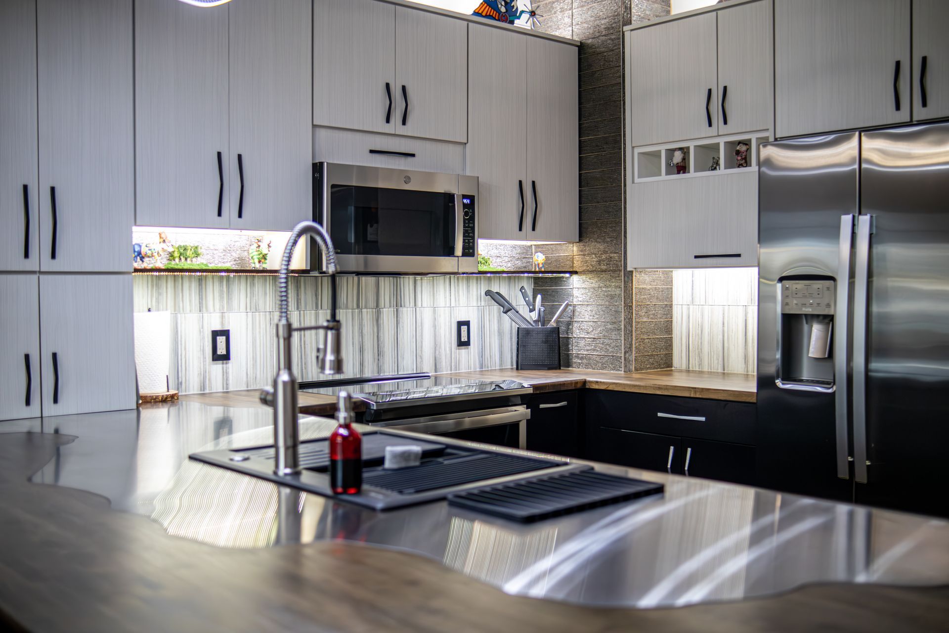 Modern kitchen with gray cabinets, stainless-steel appliances, and a large island sink