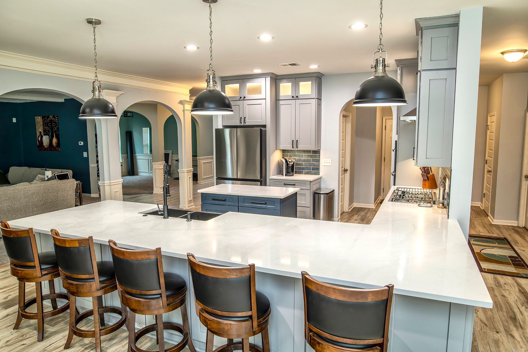 Modern kitchen with large white island, bar stools, pendant lights, and stainless steel appliances