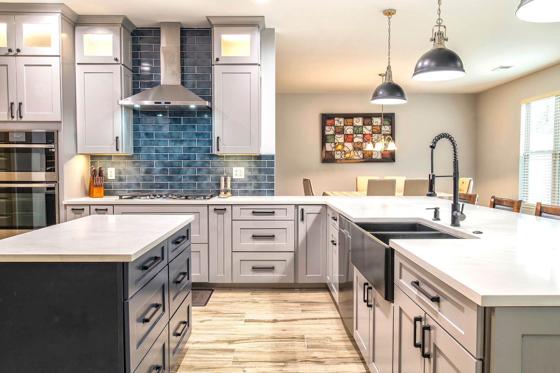Modern kitchen with gray cabinets, white countertops, blue tile backsplash, and island seating