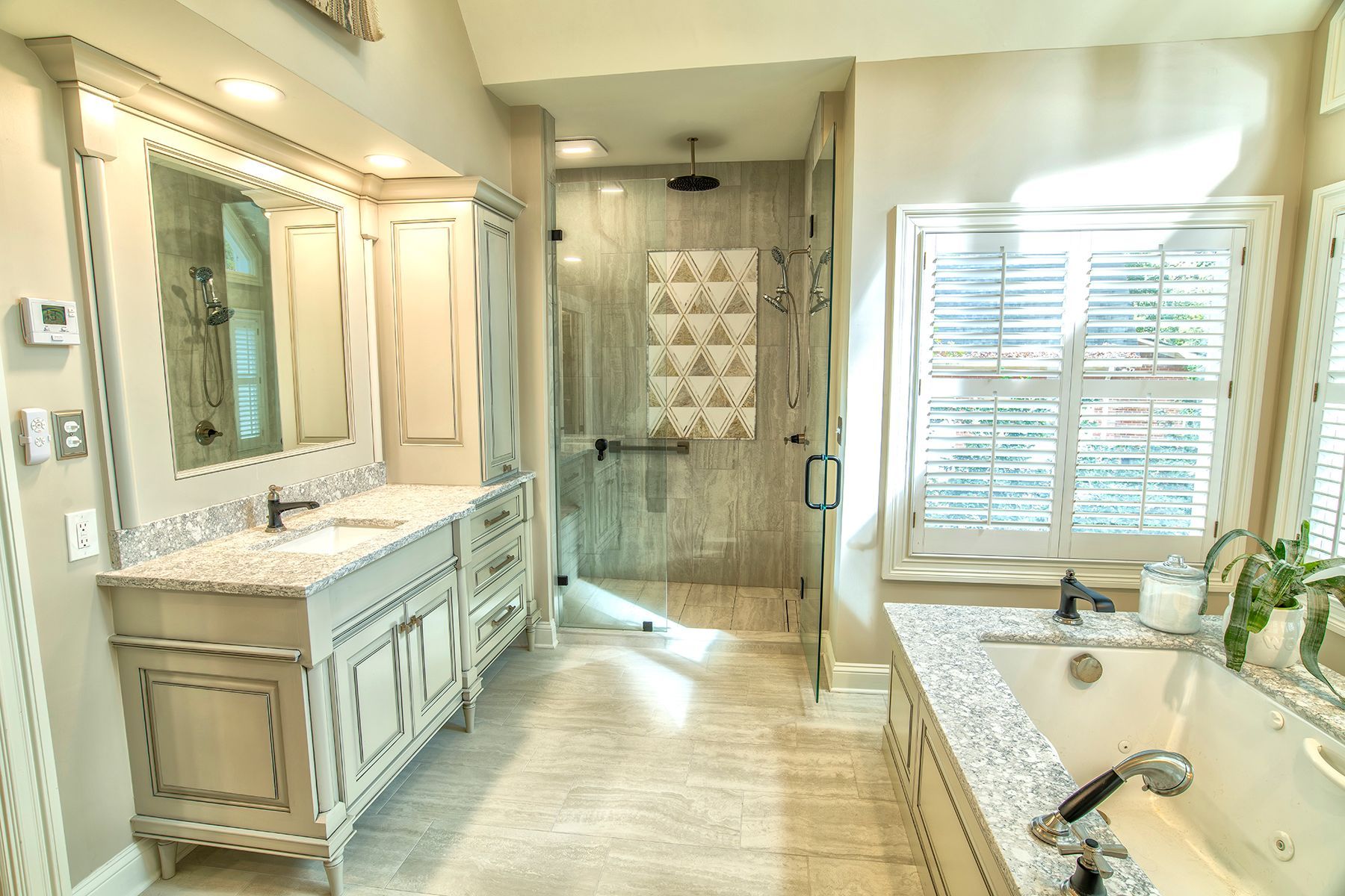 Bright bathroom with double vanity, large mirror, walk-in shower, and window blinds.