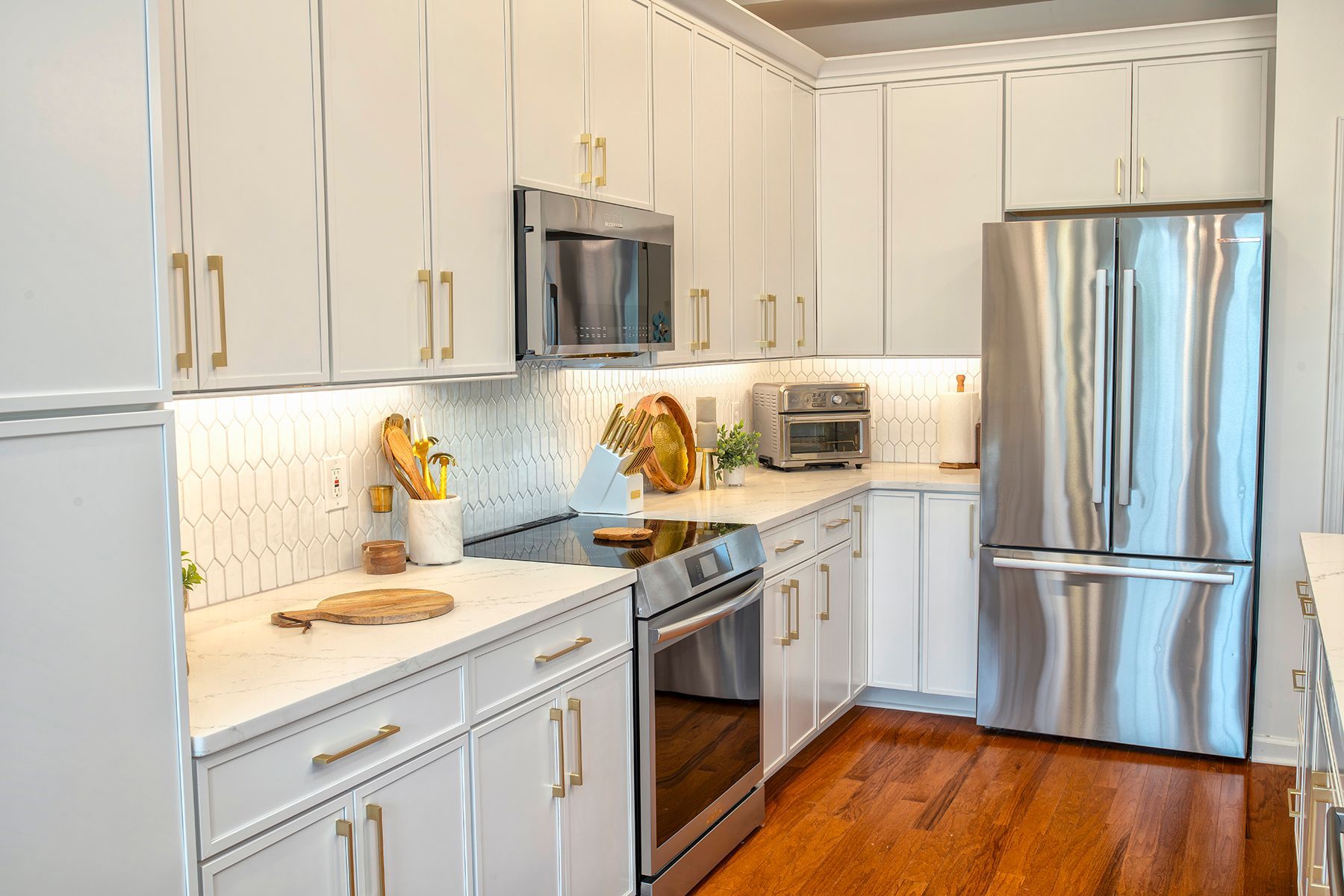Bright modern kitchen with white cabinets, stainless steel appliances, and hardwood floors