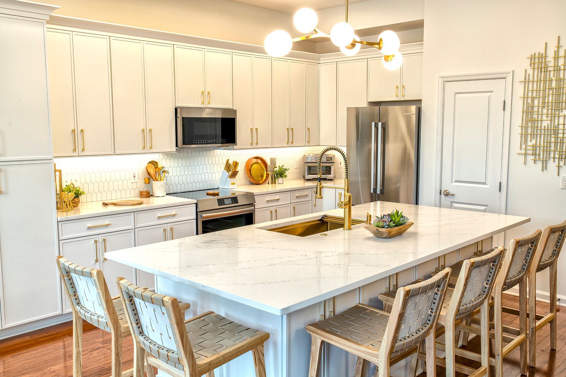 Bright white kitchen with island, bar stools, stainless fridge, and pendant lights