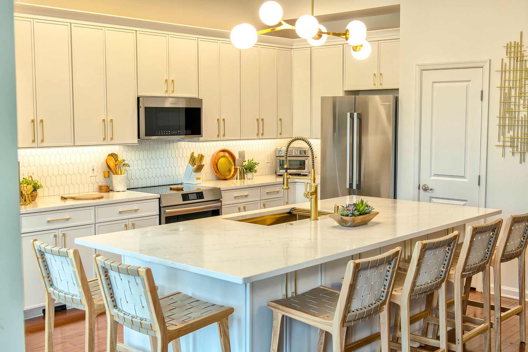Bright white modern kitchen with island seating, pendant lights, stainless steel appliances, and stools