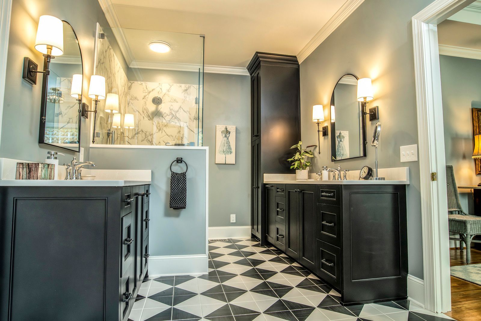 Modern bathroom with black-and-white tile floor, dark vanities, mirrors, and wall sconces