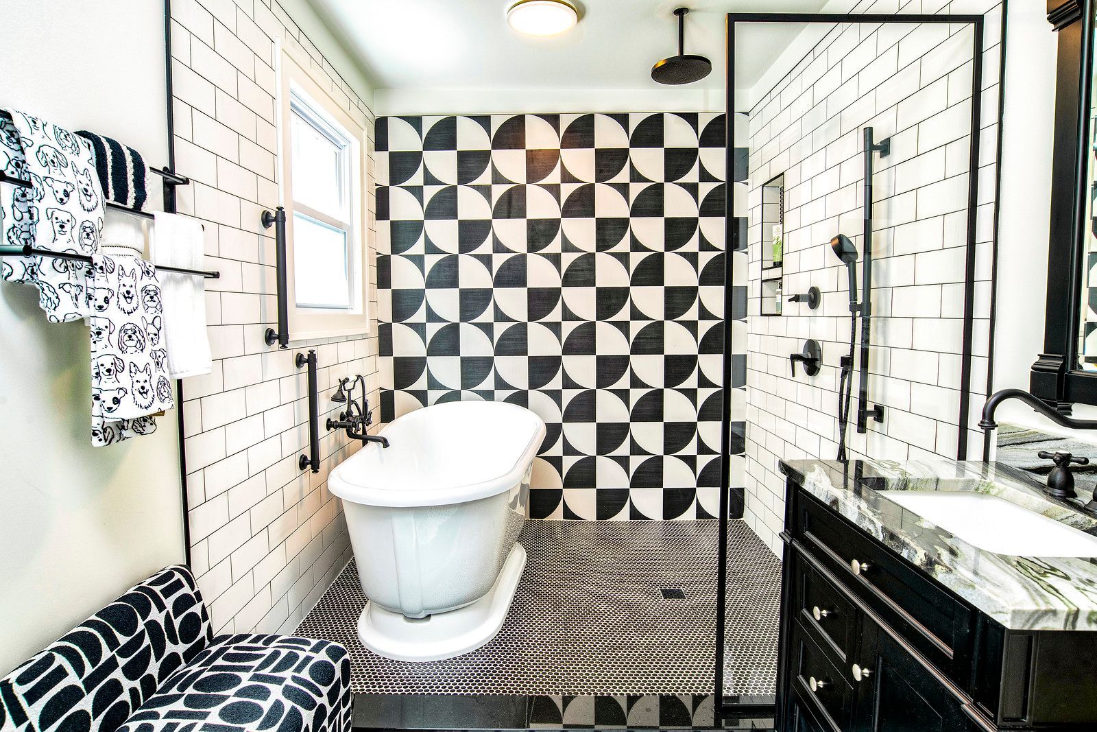 Modern bathroom with black-and-white tile, freestanding tub, and vanity.