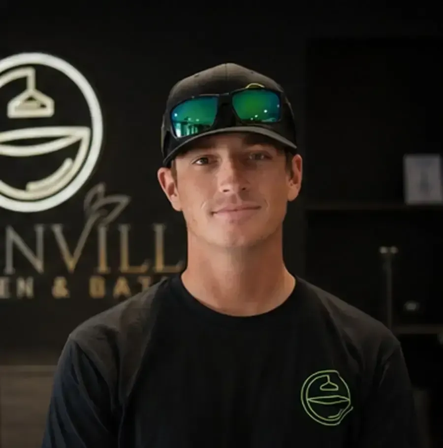 Portrait of a man in a black cap and shirt standing in front of a brewery sign