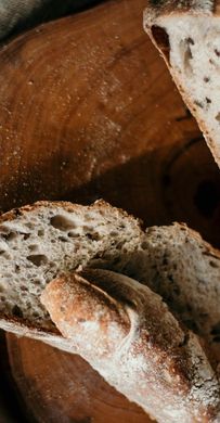 A close up of a loaf of bread sitting on top of a wooden table. A close up of a loaf of bread sitting on top of a wooden table.