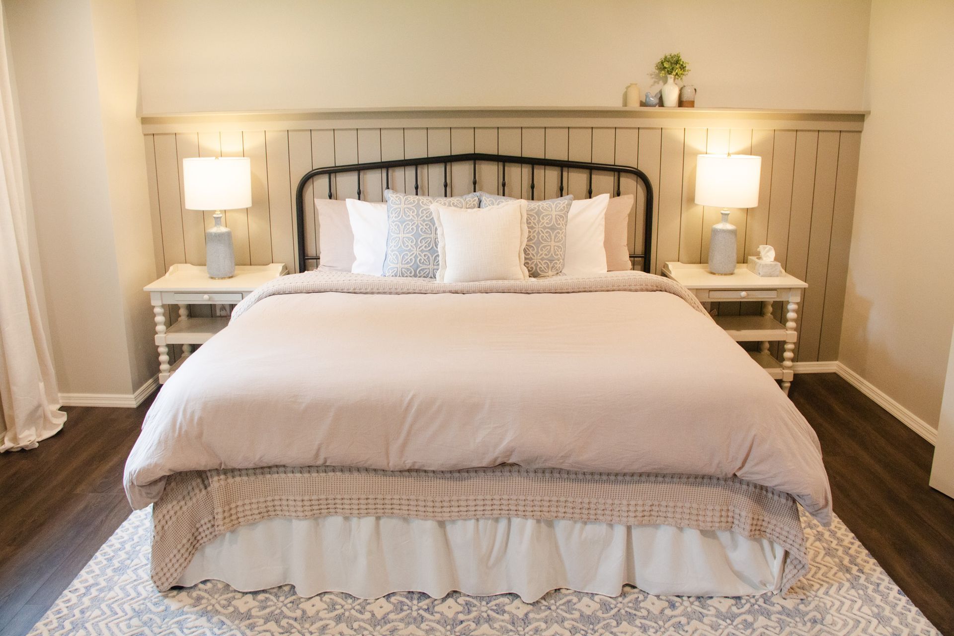 A bedroom with a king size bed , nightstands , lamps and a rug.