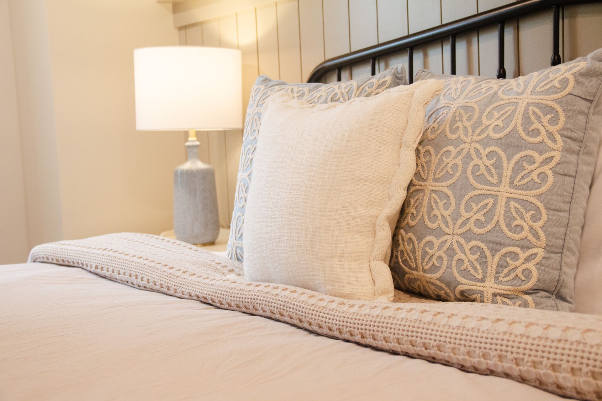 A bed with a lamp and pillows on it in a bedroom.