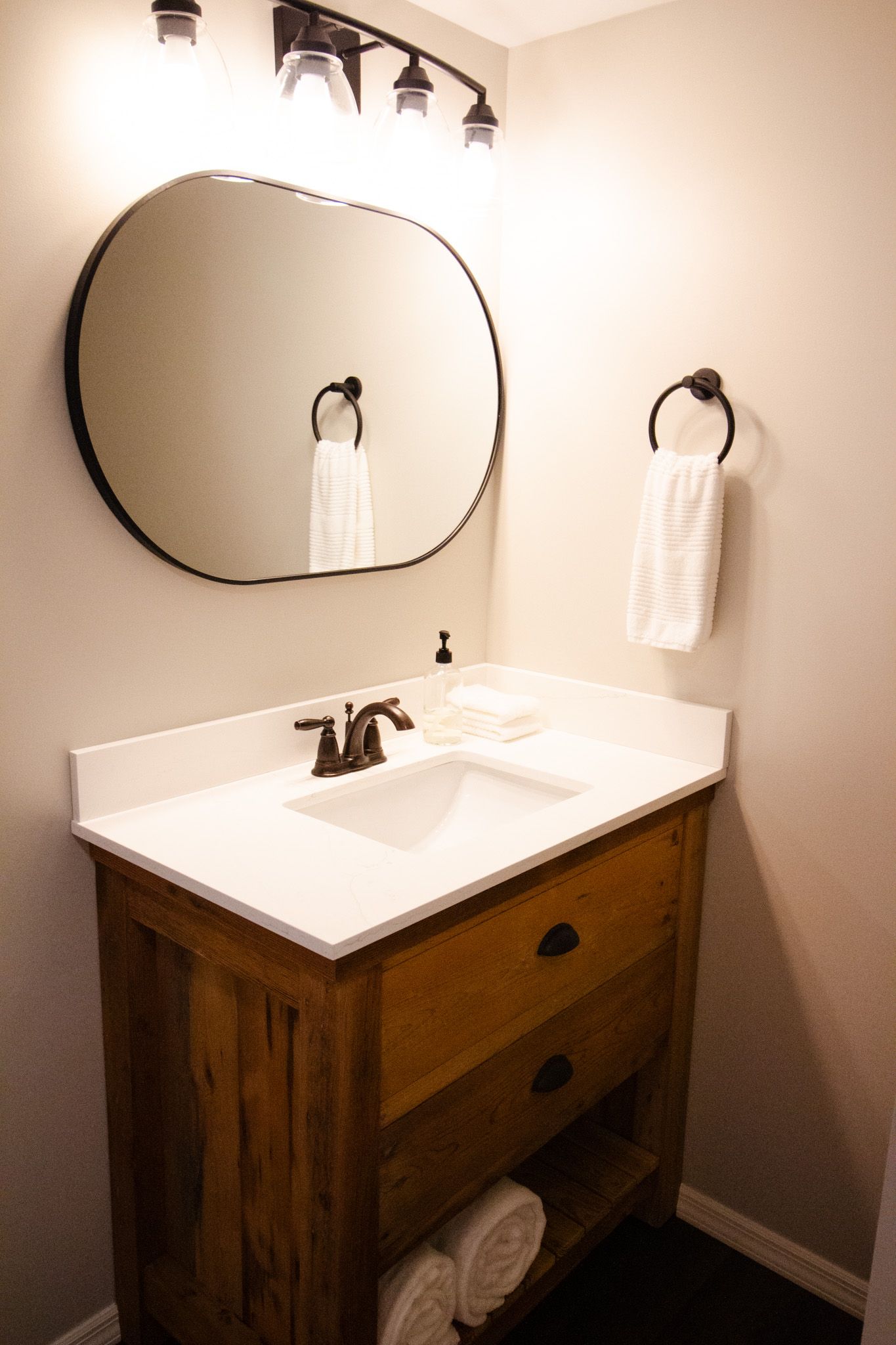A bathroom with a sink , mirror and towels.